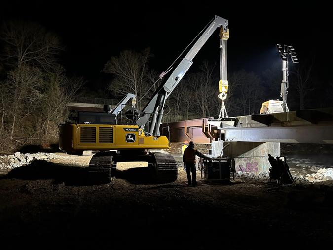 Bridge assembly continues at 4:00 a.m. on April 9. The first train over the completed bridge is shown in photo at top. Bridge assembly continues at 4:00 a.m. on April 9. The first train over the completed bridge is shown in photo at top.