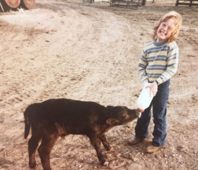Lambley bottle-feeding a calf in her childhood Lambley bottle-feeding a calf in her childhood
