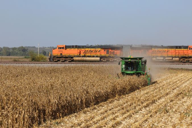 A BNSF train passes a farmer harvesting corn A BNSF train passes a farmer harvesting corn