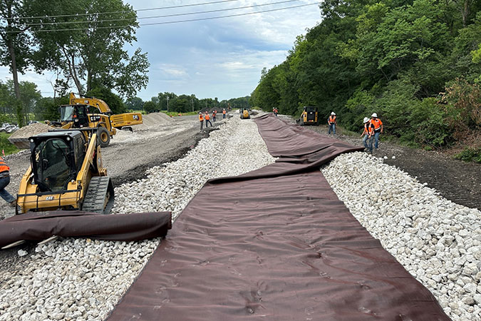 BNSF teams place rock base layer and overlaying geotextile fabric to help with stabilization. BNSF teams place rock base layer and overlaying geotextile fabric to help with stabilization.